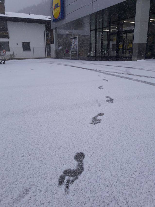 Barfußspuren im Schnee vor einem Supermarkt